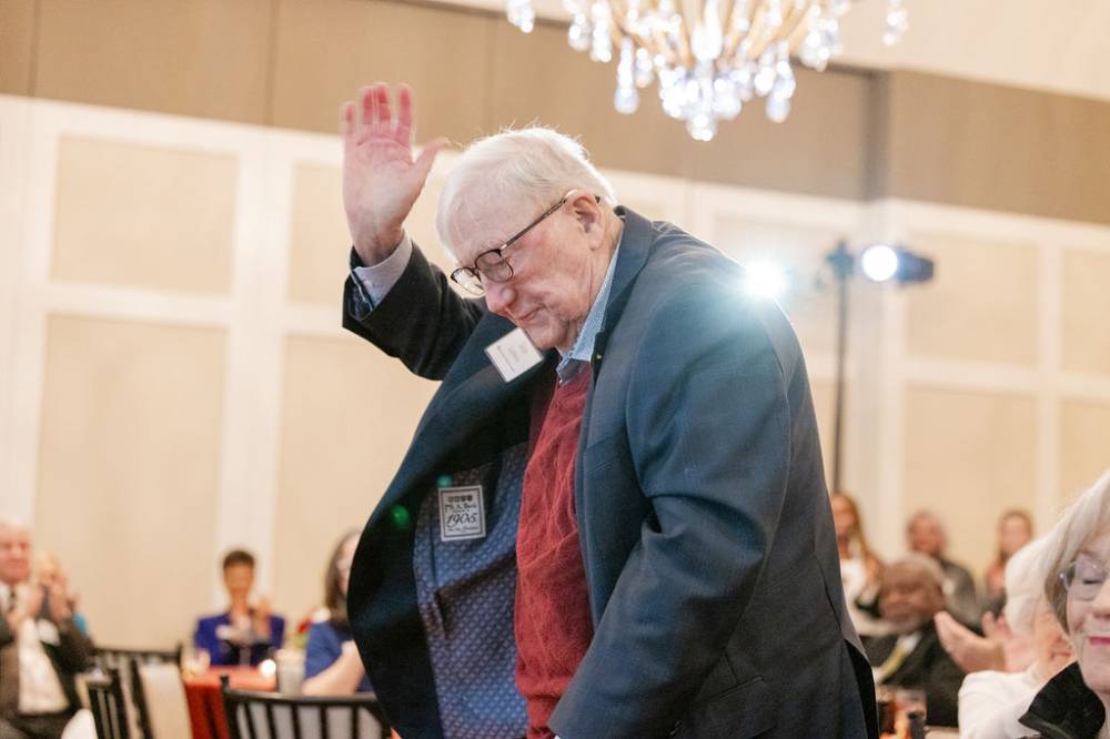 Don Lubbers, standing and being acknowledged by crowd, seen clapping in the background